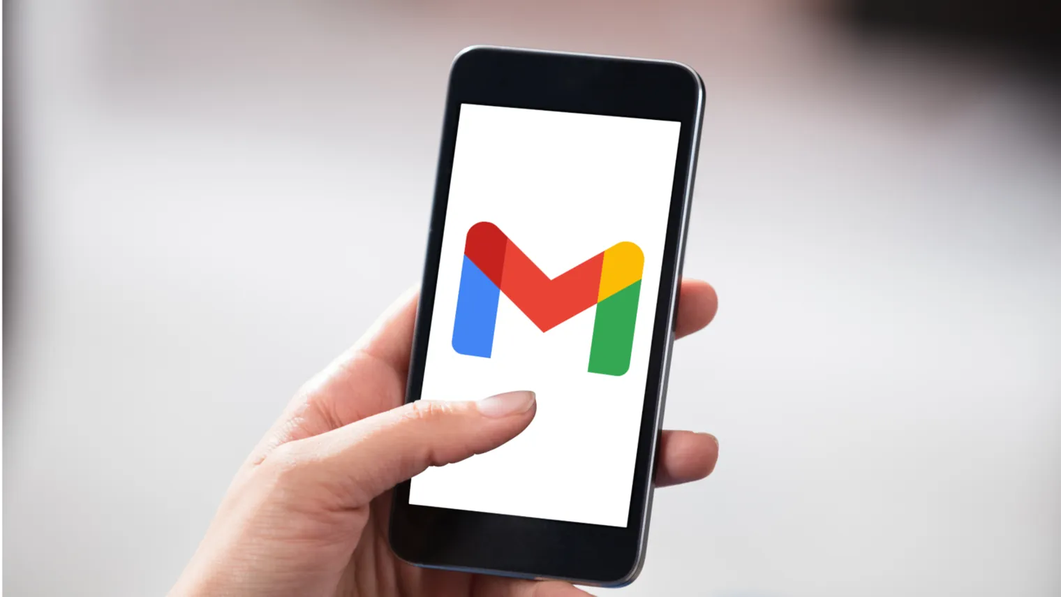 Mão segurando um smartphone com a logo do Gmail